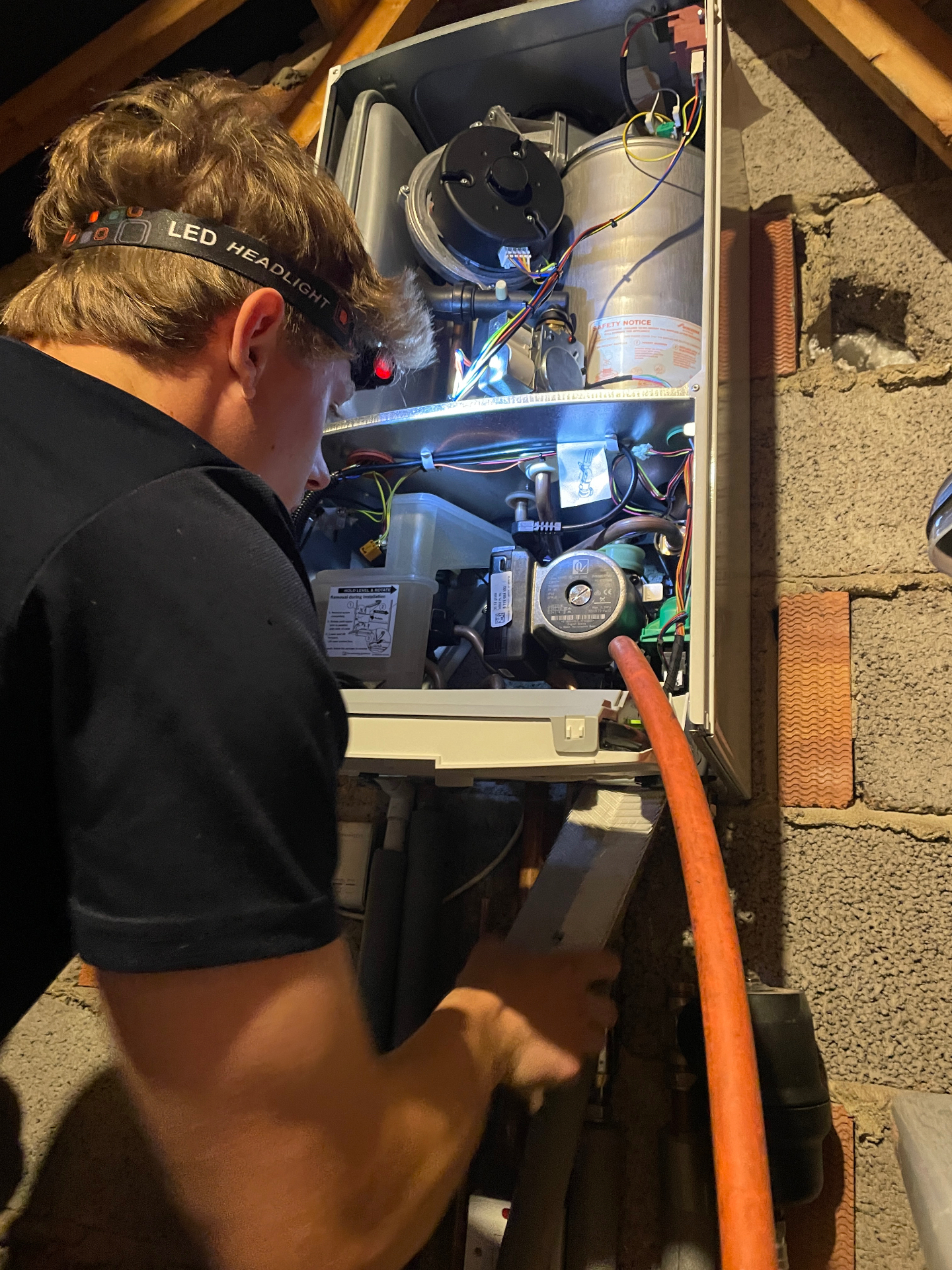 Flowtech Heating engineer servicing a boiler in a loft